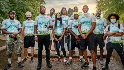 A group of 11 people pose for the camera on a wooded trail